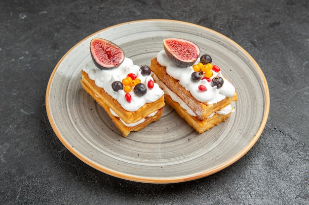 Front view yummy waffle cakes with fruits on dark background