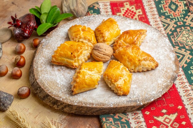 Front view yummy walnut pastries for tea on brown table pie cake sweet pastry