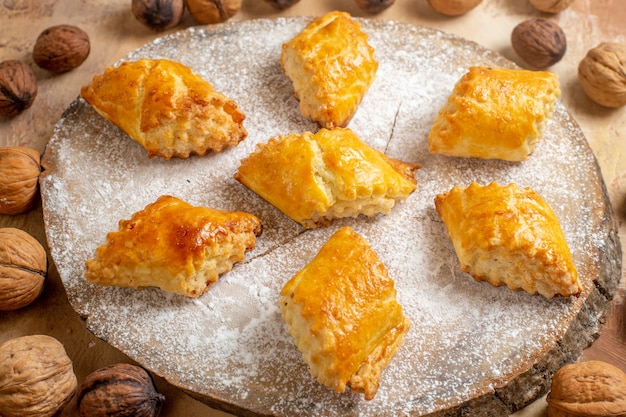 Front view yummy walnut pastries with walnuts on a light table sweet pie pastry cake