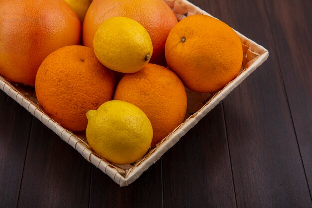 레몬과 나무 배경에 그 레이프 바구니에 정면보기 오렌지