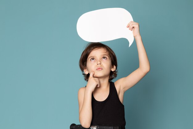 A frotn view thinking boy sweet cute adorable holding white sign in black t-shirt on the blue space