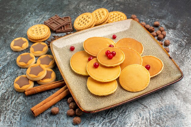 Frount view of yummy round pancakes and sweets on grey ground