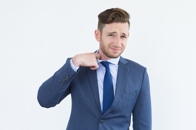 Frowning young businessman taking off tie