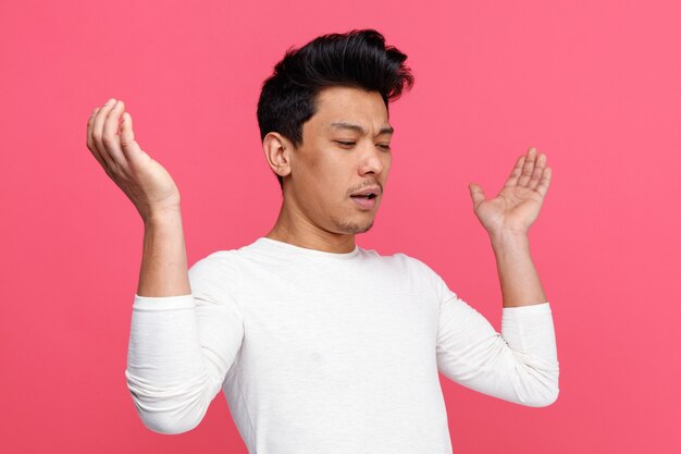 Frowning young man looking down showing empty hands 