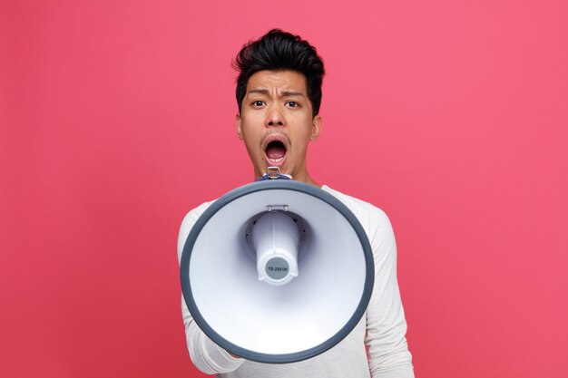 Frowning young man shouting in loud speaker 