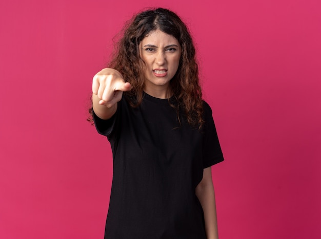 Free photo frowning young pretty woman looking and pointing at front isolated on crimson wall with copy space