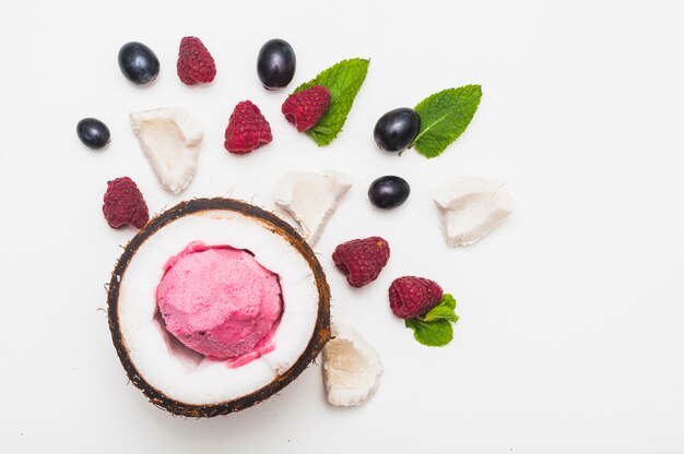 Frozen ice cream inside the coconut with raspberry; mint and grapes on white background