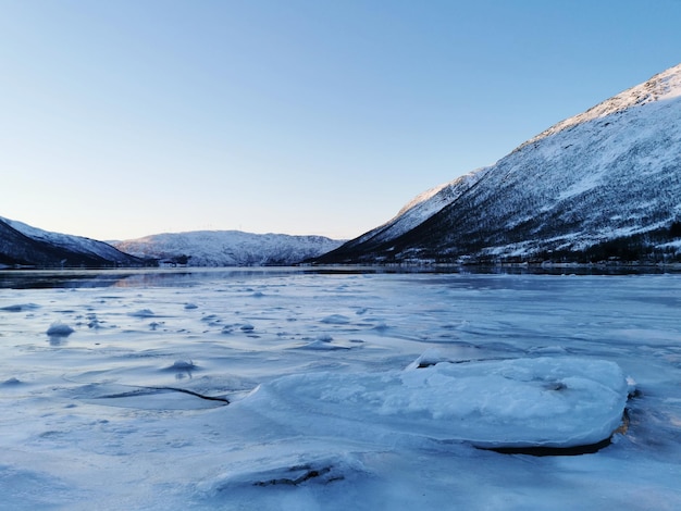 낮에 포착된 노르웨이 카트피요르덴(Kattfjorden)의 눈 덮인 언덕에 의해 얼어붙은 호수