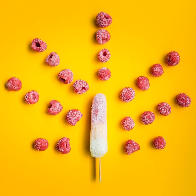 Frozen raspberries arranged near ice lolly