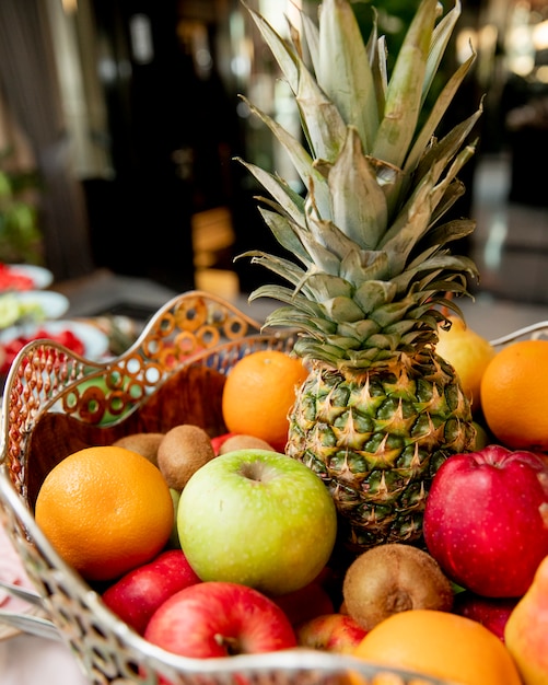 Free photo fruit basket with pineapple oranges kiwi and apples