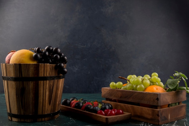 Fruit and berry mix in wooden containers on blue space