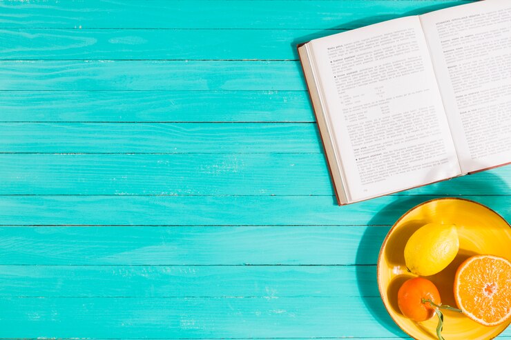 Free Photo fruit bowl and book on table