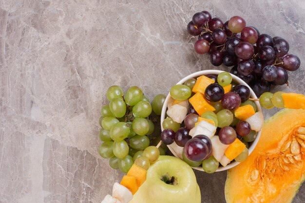 Fruit bowl and fresh fruits on marble surface.