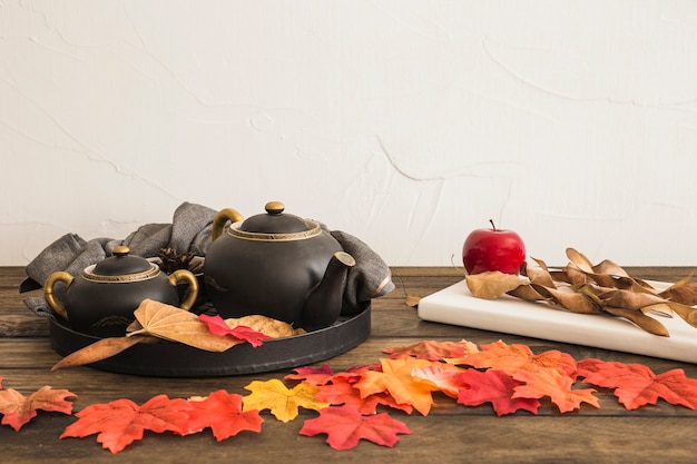 Fruit and notepad near leaves and tea set