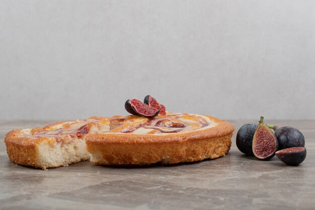 Fruit pie and fresh figs on marble wall.