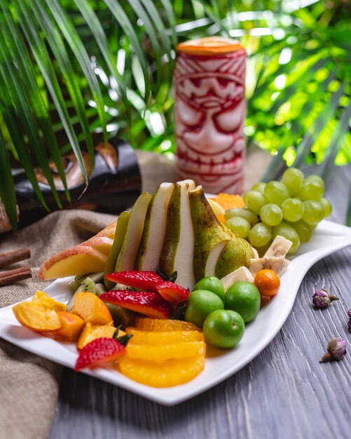 Fruit plate mandarin strawberry cherry plum banana grape peach kiwi side view