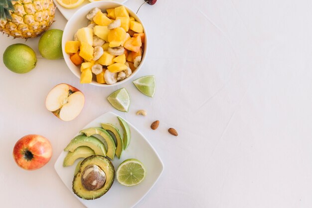Fruit salad and avocado slices on white background