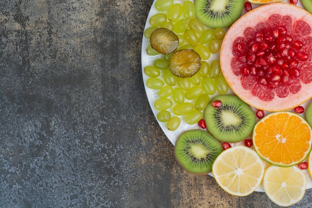 Fruit salad with pomegranate, grapefruit and kiwi on white plate. High quality photo