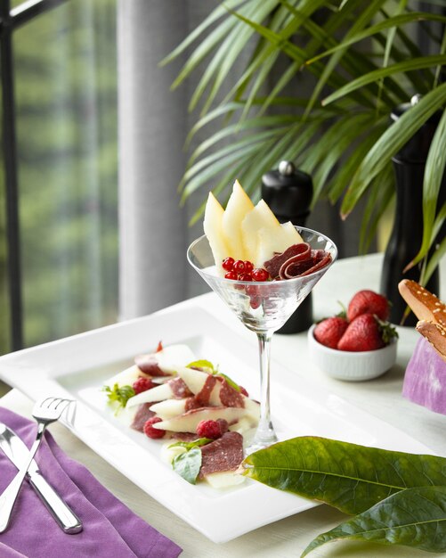 Fruit slice and berries inside glass.