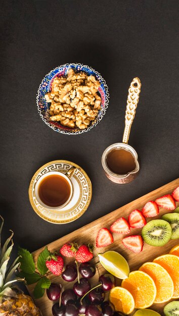 Fruit slices with tea and fresh walnut bowl on table
