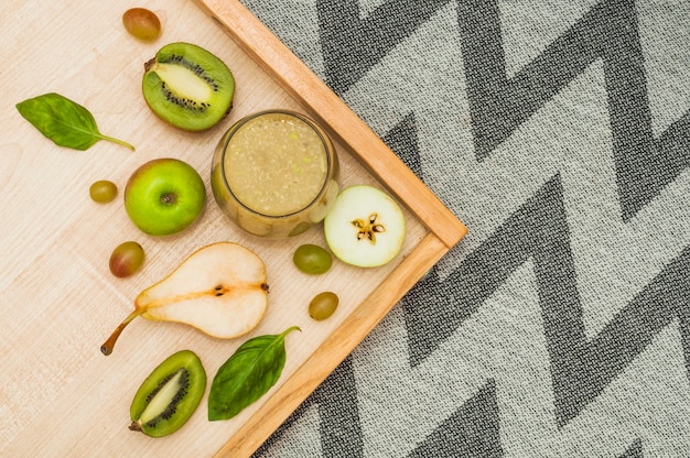 Fruit smoothie on wooden tray over the tablecloth