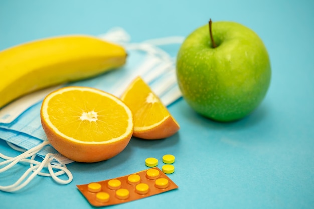 無料写真 青い背景の病気予防のコンセプトに果物と丸薬