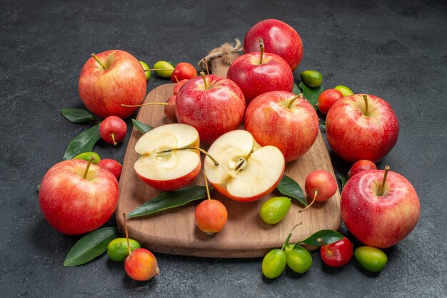 fruits apples and cherries with leaves on the board next to the fruits