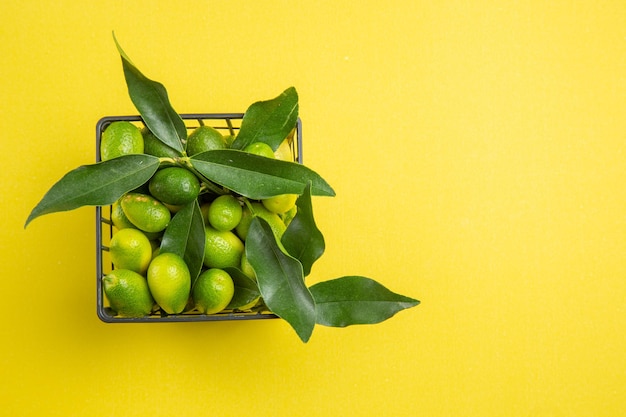 fruits in basket basket of green citrus fruits with leaves on the table