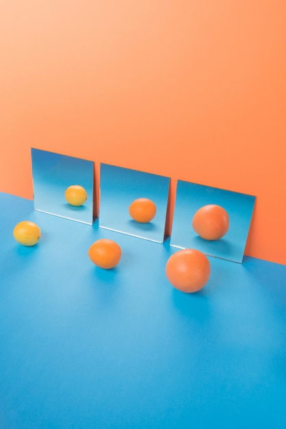 Fruits on blue table isolated on orange near mirrors