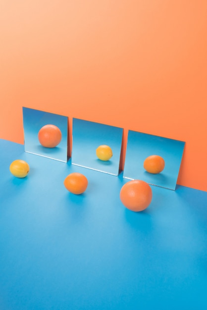 Free photo fruits on blue table isolated on orange near mirrors