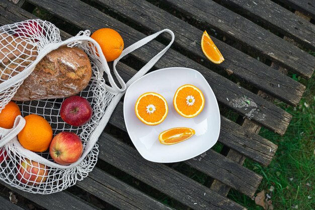 Free photo fruits and bread in a shopping bag on a wooden background