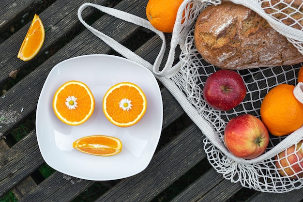 Fruits and bread in a shopping bag on a wooden background