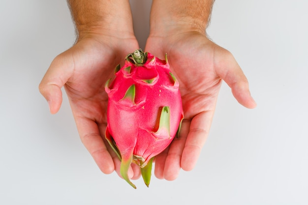 Fruits concept flat lay. hands holding dragon fruit.