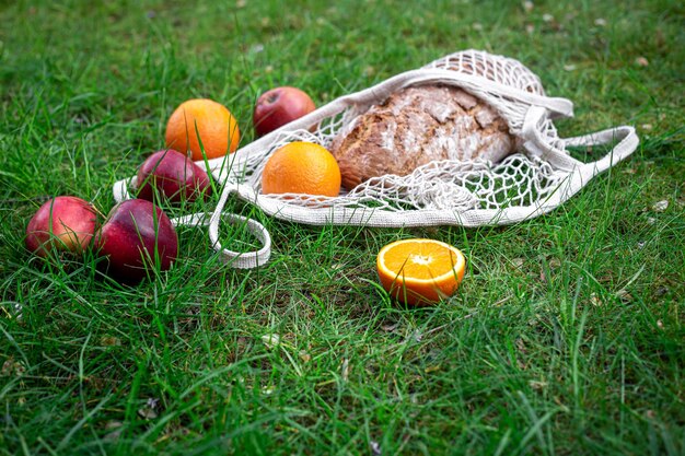 풀밭에 있는 끈 가방에 과일과 신선한 빵