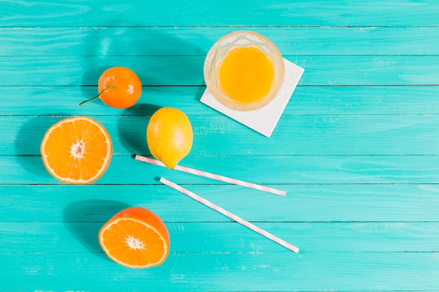 Fruits, juice glass and straws on table