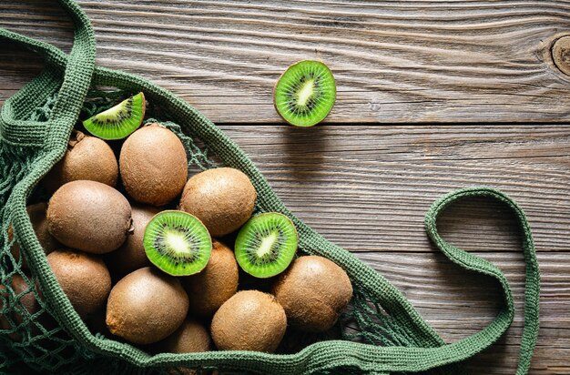 Fruits of kiwi in a mesh bag on a wooden background top view rustic style