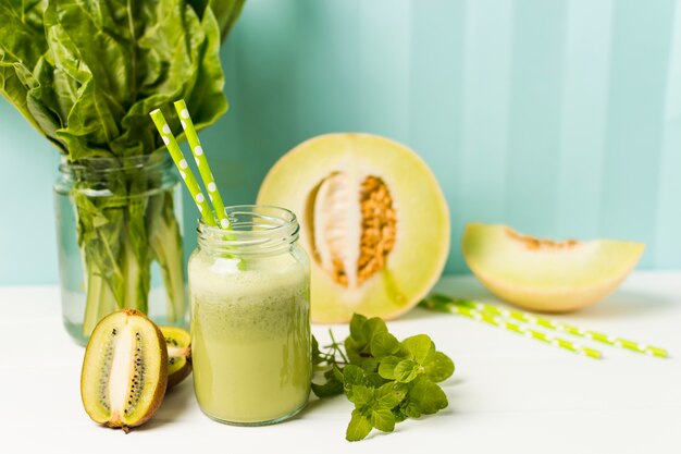 Fruits near herbs and glass with cocktail