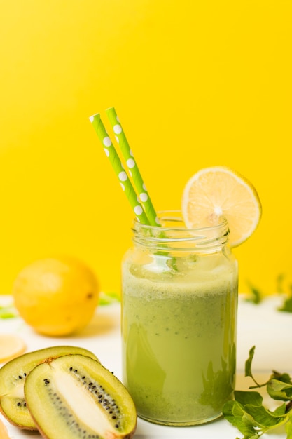 Fruits near plants and glass with cocktail and straws