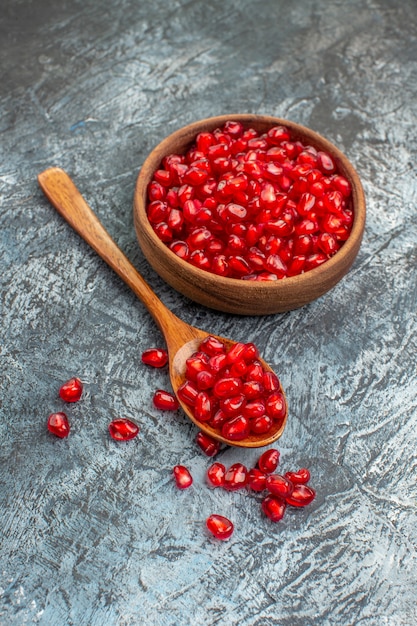 Free photo fruits seeds of pomegranate and spoon on the grey table