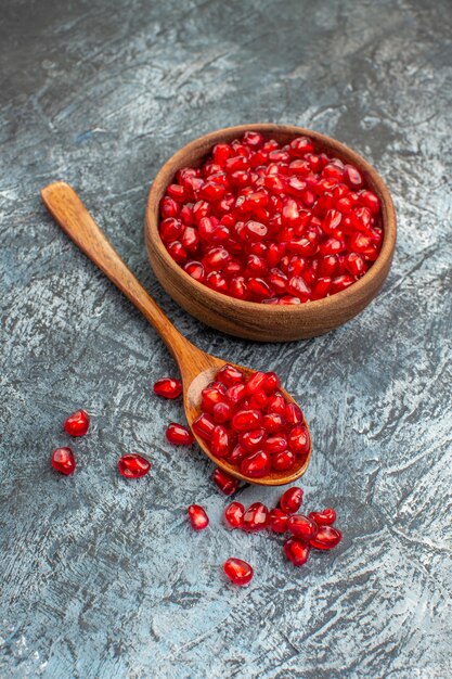 fruits seeds of pomegranate and spoon on the grey table