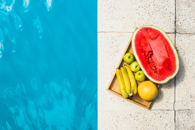 Fruits on tray placed on border of pool