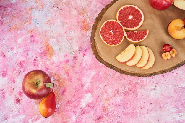 Fruits on wooden board on pink.