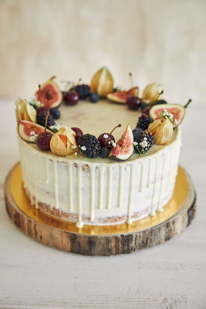 생일 토퍼가 있는 과일 생일 케이크, 위에 과일, 베이지색 배경에 흰색 물방울