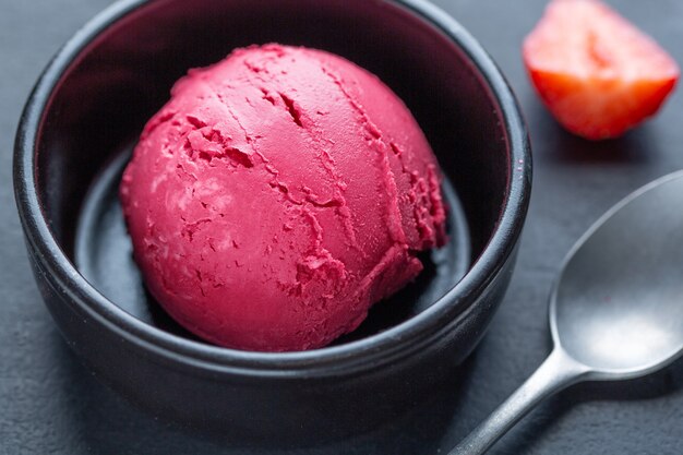 Fruity strawberry Ice cream scoop served on plate with fruits and pistacchios. Top View.