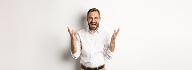 白い背景の上に立って猛烈な握手怒りで叫んで欲求不満と怒っている男