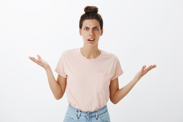 Frustrated angry young stylish woman posing against the white wall