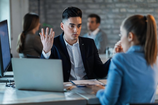 Frustrated businessman discussing with his female colleague while having a conflict in the office