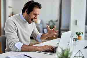 Free photo frustrated businessman shouting while working on a computer and having some problems