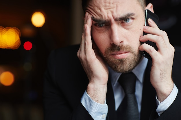 Разочарованный бизнесмен разговаривает по телефону