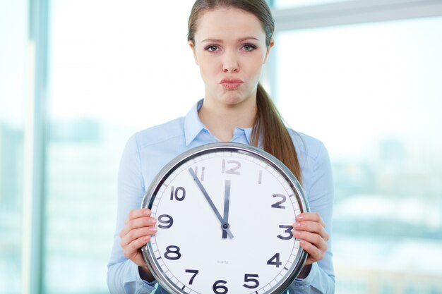 Frustrated businesswoman holding a big clock